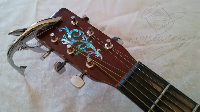 guitar neck with abalone decal and shark-shaped capo