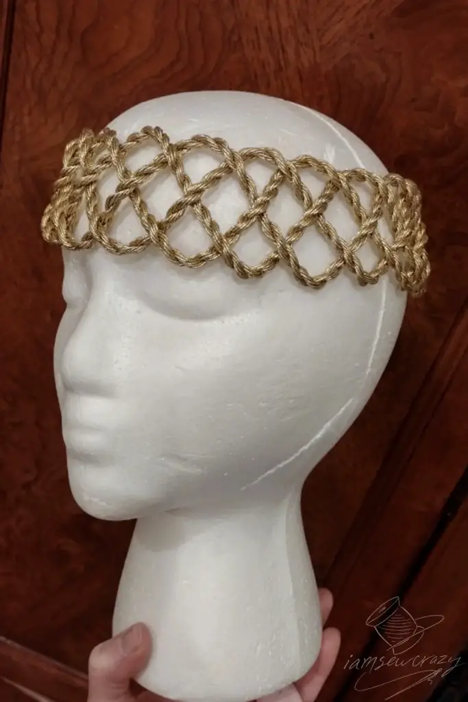 Styrofoam mannequin head wearing crown made of gold cording