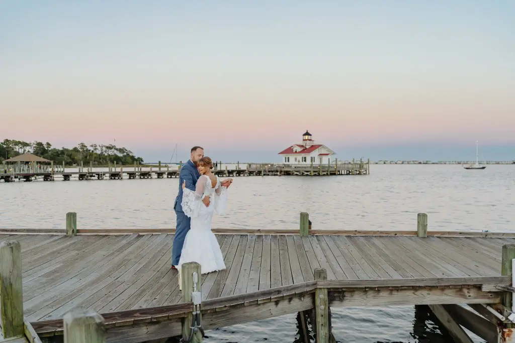 bride and groom dancing together on pier