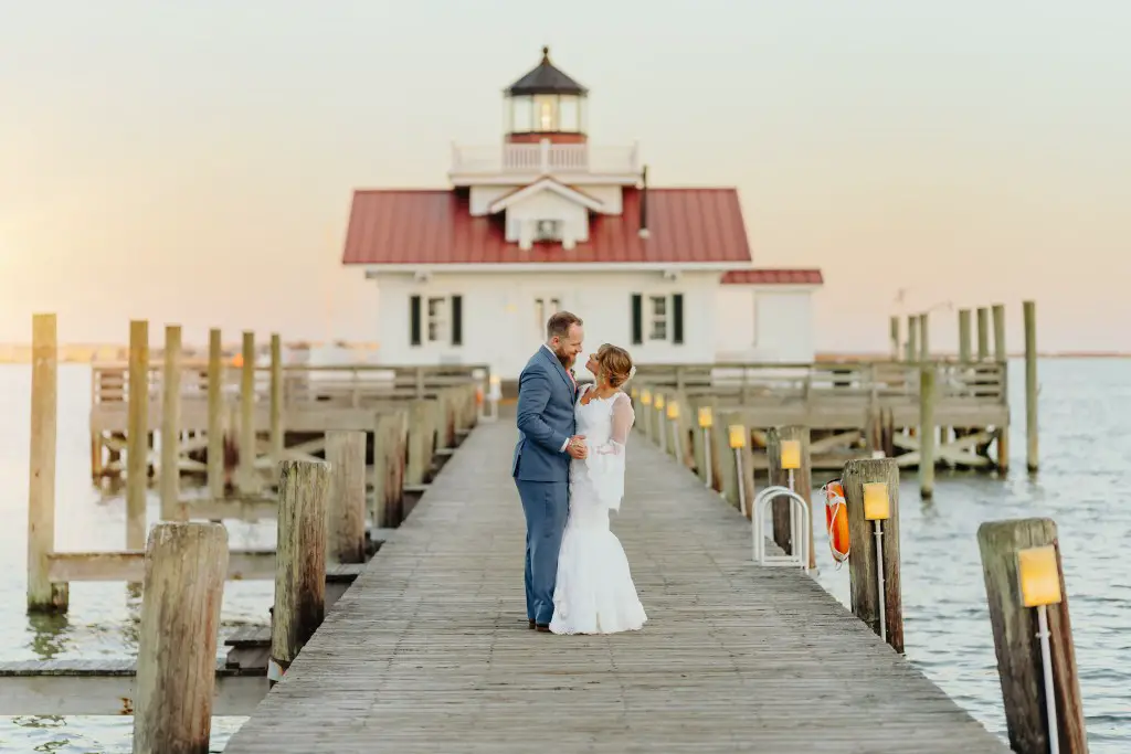 bride and groom hugging in front of lighthouse