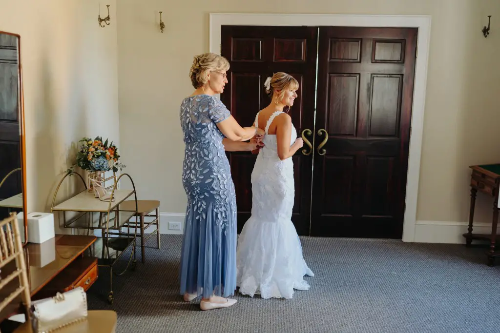 bride's mother buttoning up her restyled wedding dress