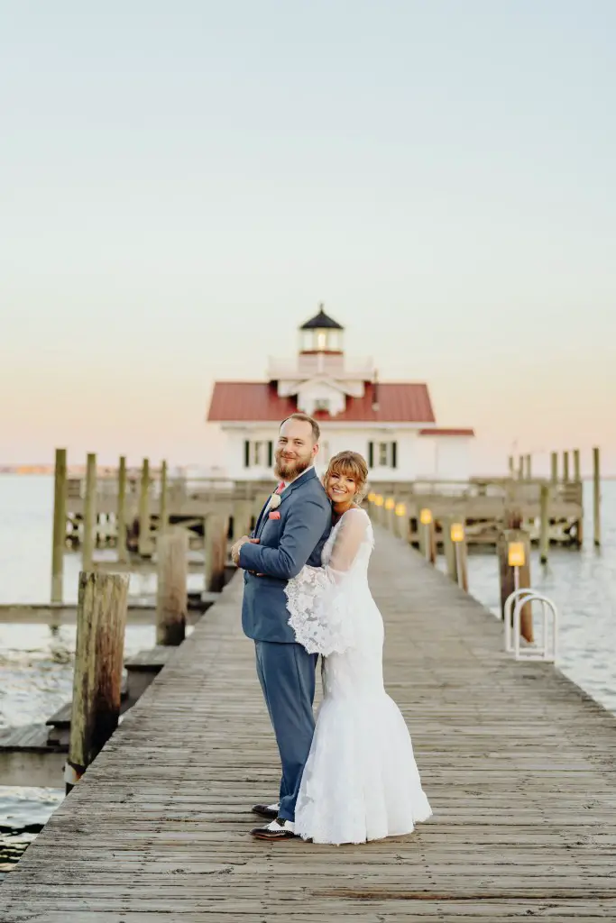 bride and groom standing in front of lighthouse