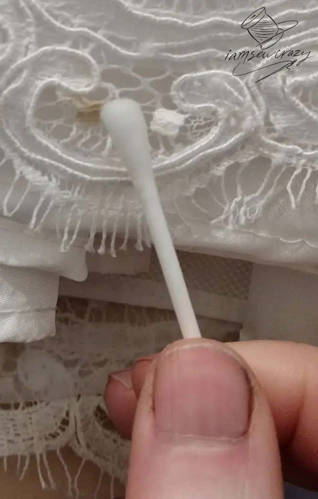 cotton swab rubbing at stain on vintage wedding dress