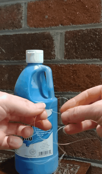 GIF image of old sewing thread being strength tested by tying it in a knot, looping it through the handle of a one-quart jug, and pulling it upwards quickly