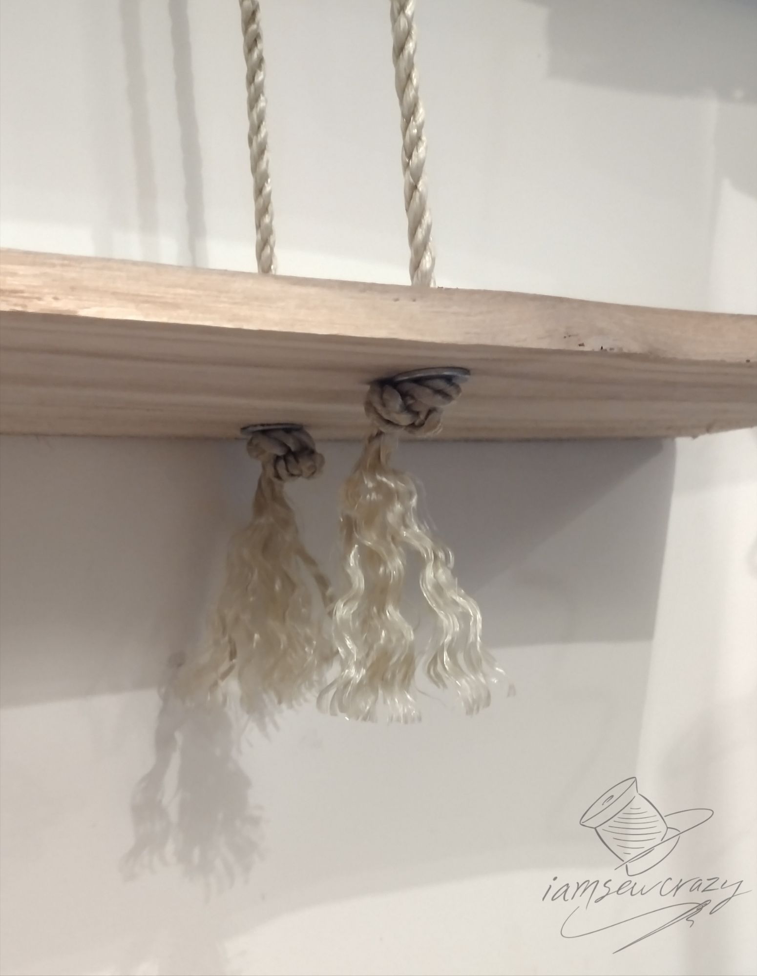 bottom of shelves that hang from ropes with ends of rope frayed into tassels