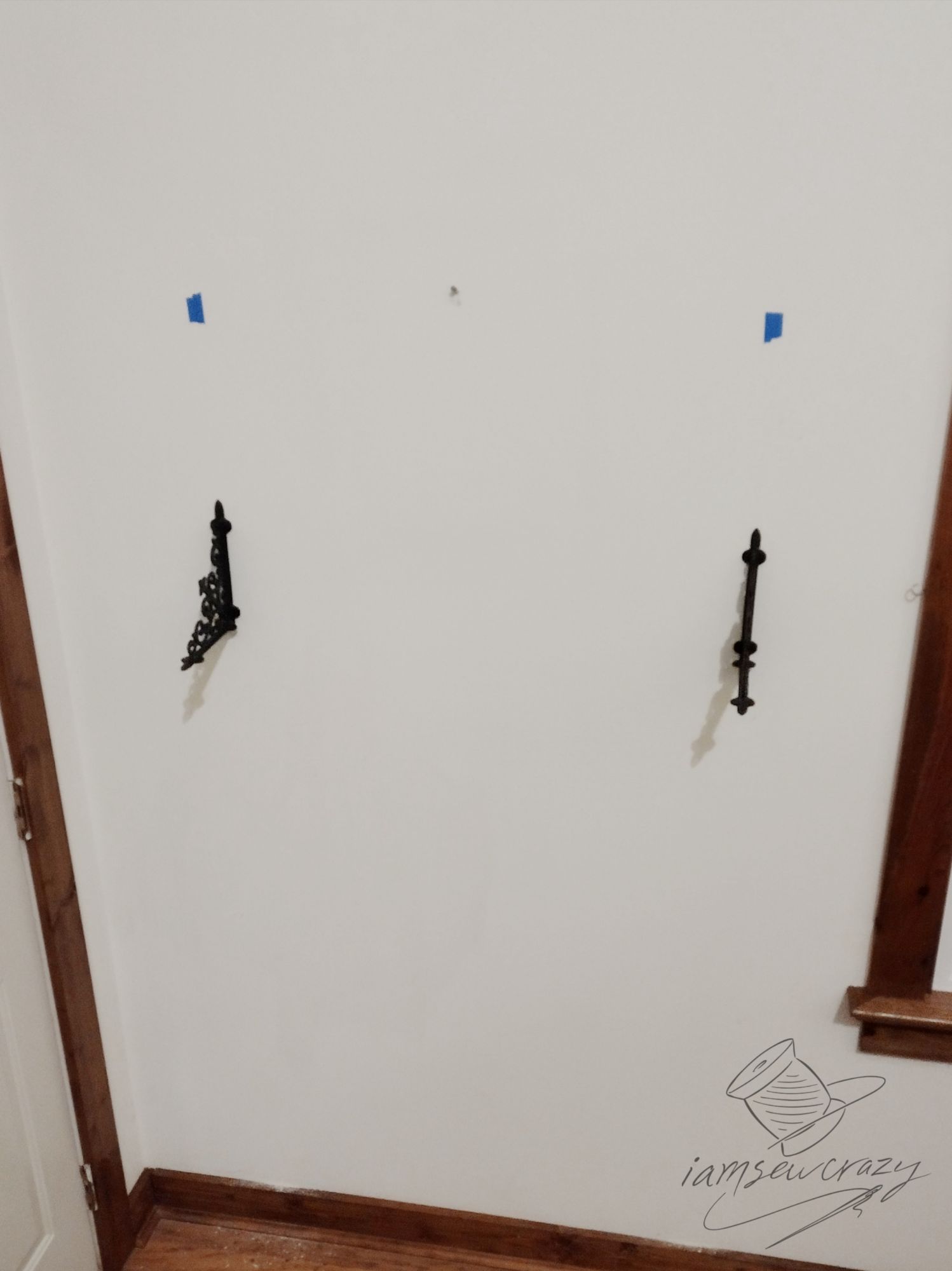 cast iron brackets screwed to wall and stud location marked with painter's tape