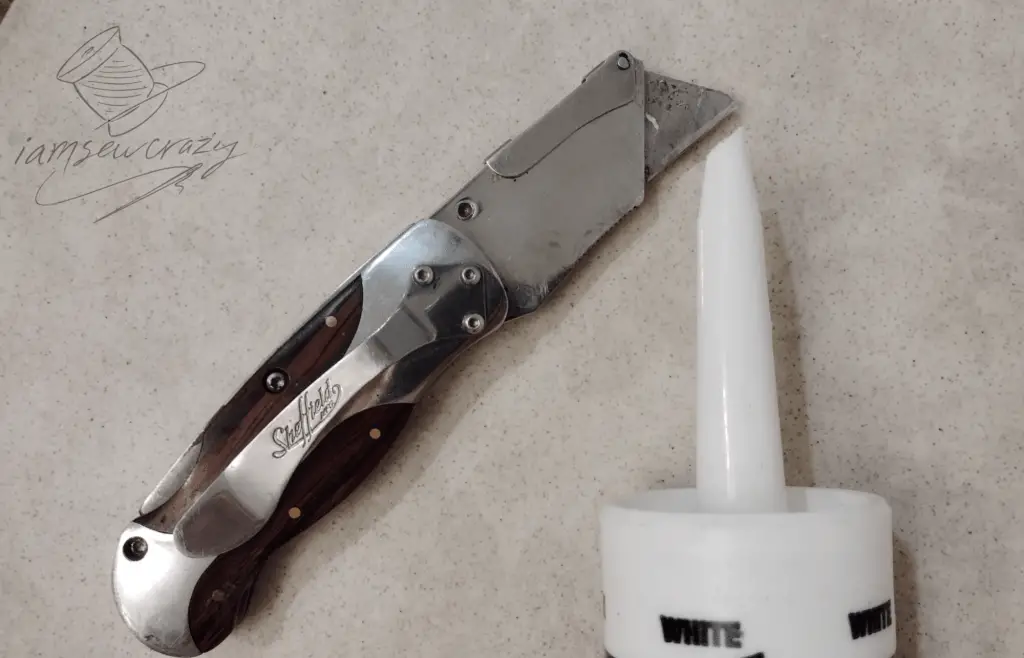 cutting tip off of caulk tube with a utility knife